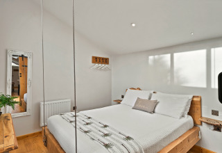 Lyst soveværelse i Hillfarrow Hideaway, UK, med træmøbler, hængeplanter og moderne indretning.