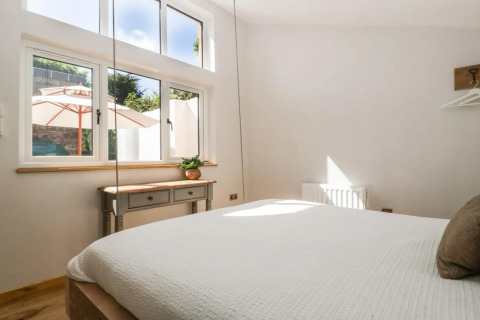 Lyst soveværelse i Hillfarrow Hideaway, Storbritannien, med store vinduer og udsigt til gårdhaven.