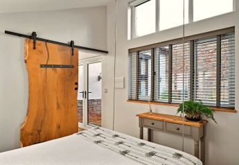Camera da letto a Hillfarrow Hideaway con porta scorrevole in legno grezzo, persiane e arredamento accogliente.