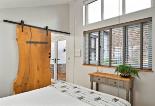 Soveværelse ved Hillfarrow Hideaway med naturtræsskydedør, vinduer med persienner og grønt interiør.