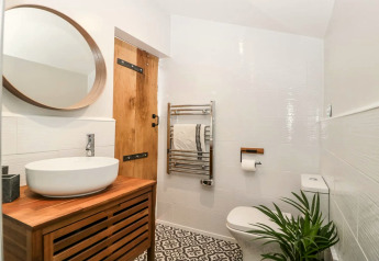 Bagno moderno al Hillfarrow Hideaway nel Regno Unito, con dettagli in legno, lavabo e pianta verde decorativa.