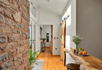 Ingresso luminoso a Hillfarrow Hideaway, Regno Unito, con parete in pietra, banco rustico e arredo accogliente.