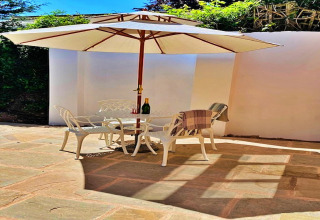 Udendørs terrasse ved Hillfarrow Hideaway, England, med stole, bord, parasol og solskin.