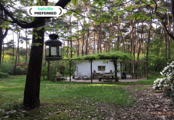 El chalet Het Beerenbos en el bosque, con terraza exterior y vegetación frondosa primaveral.