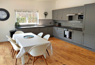Moderne køkken og spiseområde i Little Dunley - Apple Lodge i Storbritannien med grå skabe og trægulv.