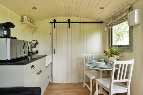 Angolo cucina e zona pranzo accoglienti nella cabina Hay and Hedgerow Glamping con comfort moderni nel Regno Unito.