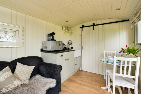 Interni accoglienti della cabina Hay and Hedgerow Glamping con angolo cottura e zona pranzo nel Regno Unito.