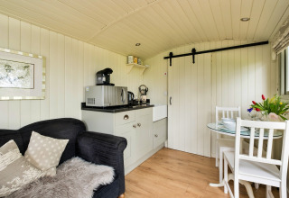 Interni accoglienti della cabina Hay and Hedgerow Glamping con angolo cottura e zona pranzo nel Regno Unito.