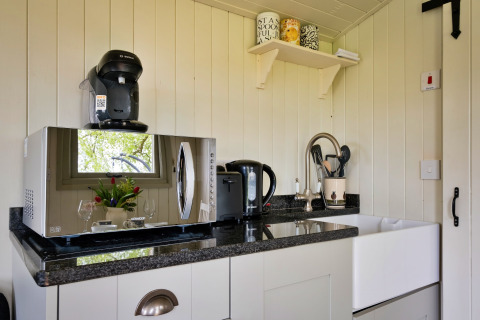 Angolo cottura luminoso con microonde, macchina del caffè, bollitore e lavello in Hay and Hedgerow Glamping, UK.
