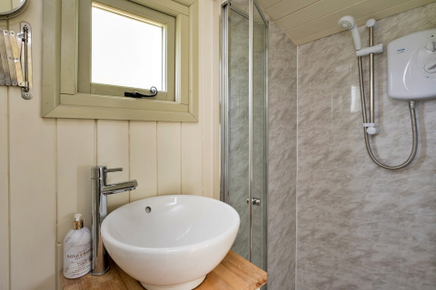 Piccolo bagno moderno a Hay and Hedgerow Glamping, Regno Unito, con lavabo rotondo, doccia e finestra.