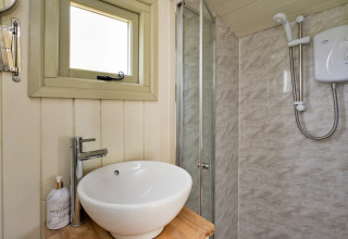 Piccolo bagno moderno a Hay and Hedgerow Glamping, Regno Unito, con lavabo rotondo, doccia e finestra.