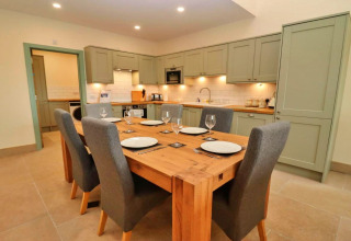 Moderne keuken en eetruimte in Little Rissington - Barn Four lodge met houten tafel en grijze stoelen.