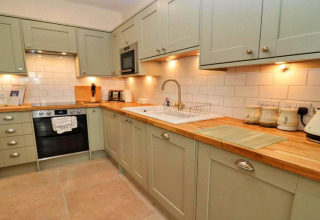 Moderne keuken in Little Rissington - Barn Four, Verenigd Koninkrijk, met houten werkblad en lichte kasten.
