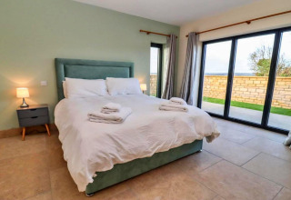 Moderne slaapkamer met dubbel bed, nachtkastjes en grote ramen in Little Rissington - Barn Four, VK.