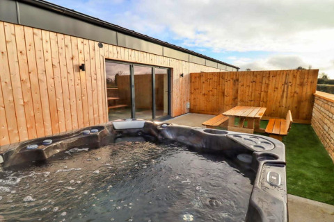 Buitenzone bij Little Rissington - Barn Four met jacuzzi, terras en houten banken in het Verenigd Koninkrijk.