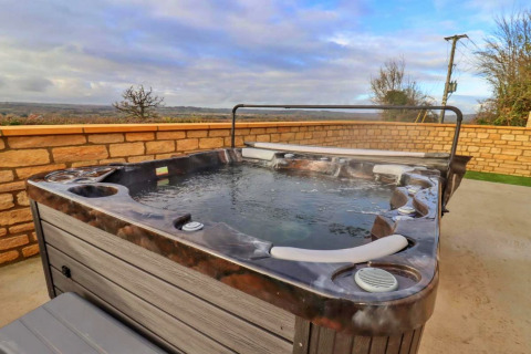 Bubbelbad buiten op het terras bij Little Rissington - Barn Four, met zicht op het Engels landschap.