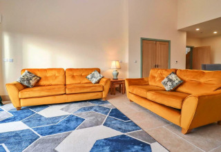 Knusse woonkamer bij Little Rissington - Barn Four, VK, met twee oranje zetels en een blauw vloerkleed.