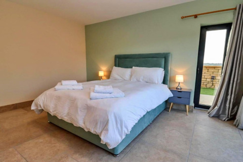 Moderne slaapkamer in Little Rissington - Barn Four met dubbel bed, nachtkastjes en een raam in het Verenigd Koninkrijk.