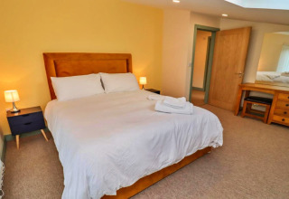 Slaapkamer met tweepersoonsbed, nachtkastjes, lampen en kaptafel bij Little Rissington - Barn Four, Verenigd Koninkrijk.