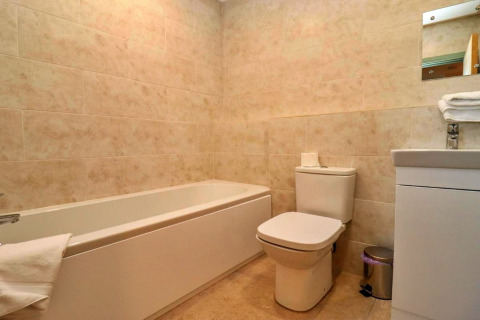 Moderne badkamer met bad, toilet, wastafel en spiegel in Little Rissington - Barn Four, Verenigd Koninkrijk.