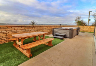Buitenzone van Little Rissington - Barn Four in het VK met houten picknicktafel en jacuzzi.