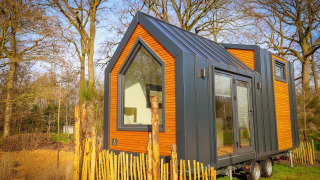 Casa diminuta y moderna con revestimiento de madera y metal, ubicada en el bosque de Holiday Park Sallandshoeve.