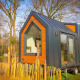 Moderne tiny house på hjul med sort og træbeklædning i skovmiljø ved Holiday Park Sallandshoeve, Holland.