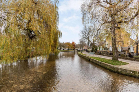 Rivier met hangende bomen naast terras van Little Rissington - Barn Four Lodge in het Verenigd Koninkrijk.