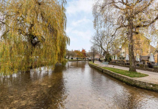 Rivier met hangende bomen naast terras van Little Rissington - Barn Four Lodge in het Verenigd Koninkrijk.