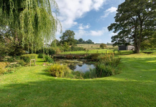 Vredig uitzicht op een vijver en groene tuin bij Little Rissington - Barn Four lodge in het Verenigd Koninkrijk.