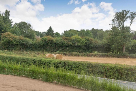 Zicht op een veld met hooibalen en groene bomen bij Little Rissington - Barn Four in het Verenigd Koninkrijk.