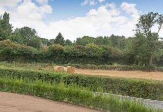 Zicht op een veld met hooibalen en groene bomen bij Little Rissington - Barn Four in het Verenigd Koninkrijk.