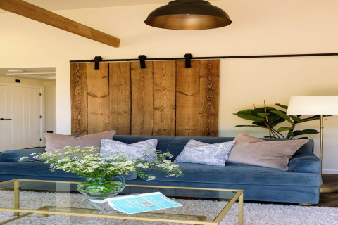 Soggiorno con divano blu, cuscini, porta scorrevole in legno e tavolo in vetro a Blackbarn Wood, Regno Unito.