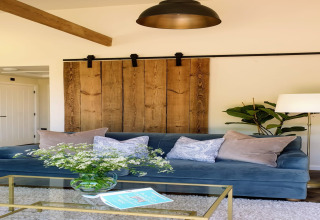 Soggiorno con divano blu, cuscini, porta scorrevole in legno e tavolo in vetro a Blackbarn Wood, Regno Unito.