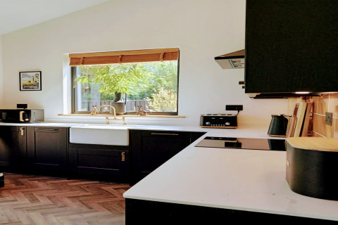 Cucina moderna con mobili neri, piani bianchi e finestra nella lodge Blackbarn Wood nel Regno Unito.