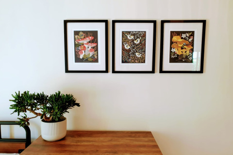 Decorazione interna a Blackbarn Wood Lodge con tre stampe botaniche incorniciate e una pianta grassa sul tavolo.