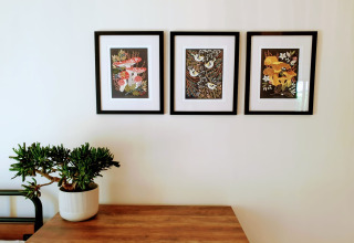 Decorazione interna a Blackbarn Wood Lodge con tre stampe botaniche incorniciate e una pianta grassa sul tavolo.
