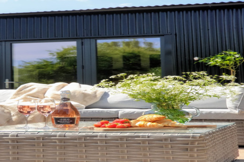 Tavolo all'aperto al lodge Blackbarn Wood nel Regno Unito con vino rosé, croissant e fiori freschi.