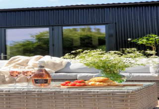 Tavolo all'aperto al lodge Blackbarn Wood nel Regno Unito con vino rosé, croissant e fiori freschi.