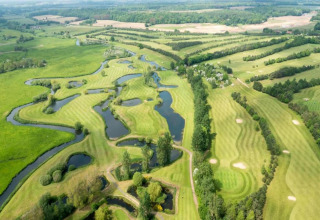 Vista aérea de un campo de golf verde con lagos y árboles cerca de Iris Bell Tent en el Reino Unido.