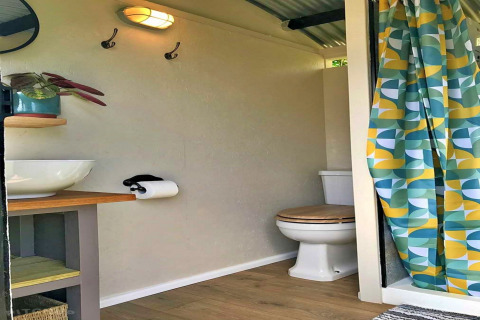 Teepee tent bathroom with a toilet, vessel sink, wood counter, and colorful geometric shower curtain.