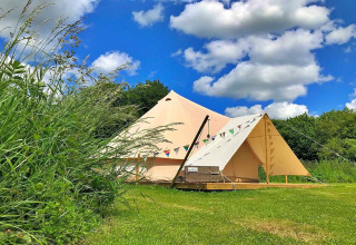 Large teepee tent at 'Meadow Glamping Tents' in the UK, set on green grass under a blue sky.