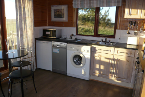 Cucina moderna nella cabina Tore Petty, Regno Unito, con lavatrice e vista panoramica dalla finestra.