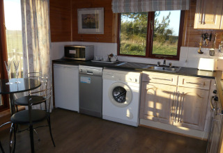 Cucina moderna nella cabina Tore Petty, Regno Unito, con lavatrice e vista panoramica dalla finestra.