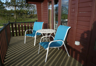 Terrazza esterna della cabina Tore Petty nel Regno Unito con due sedie blu e tavolo rotondo bianco.