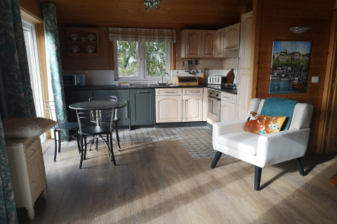 Accogliente interno della cabina «Tore Petty» nel Regno Unito con cucina, tavolo da pranzo e poltrona.