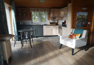Accogliente interno della cabina «Tore Petty» nel Regno Unito con cucina, tavolo da pranzo e poltrona.