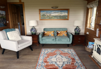 Bright, cozy living space at Tore Petty cabin in the UK with modern sofa, armchair, lamps, and wall art.