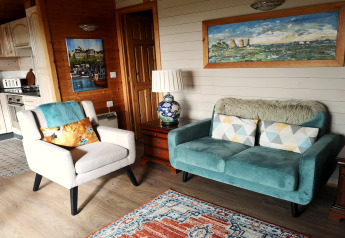 Cozy living area of Tore Petty cabin with teal sofa, armchair, and vibrant decor accents in the UK.
