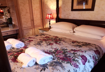 Bedroom at Tore Petty cabin, United Kingdom, with floral bedspread, pillows, and rolled white towels.